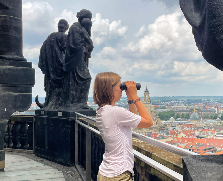 Besucherin schaut vom Rathausturm mit dem Fernglas auf Dresden