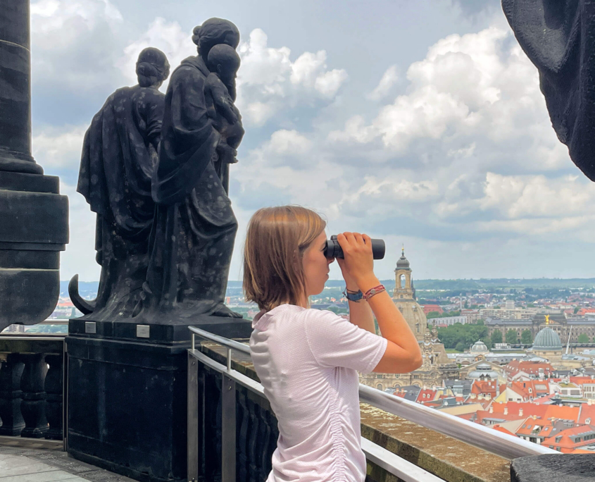 Besucherin schaut vom Rathausturm mit dem Fernglas auf Dresden