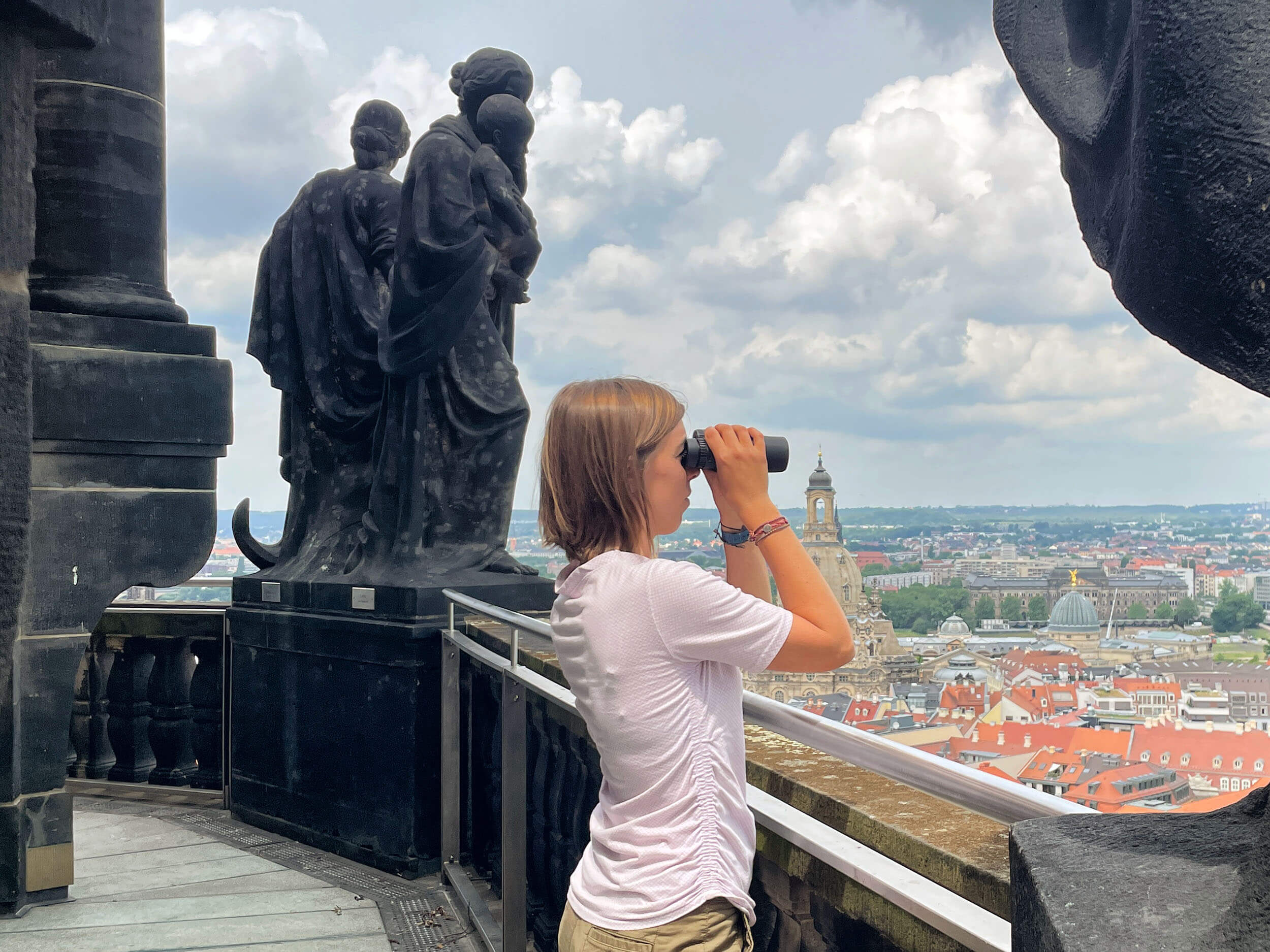 Besucherin schaut vom Rathausturm mit dem Fernglas auf Dresden